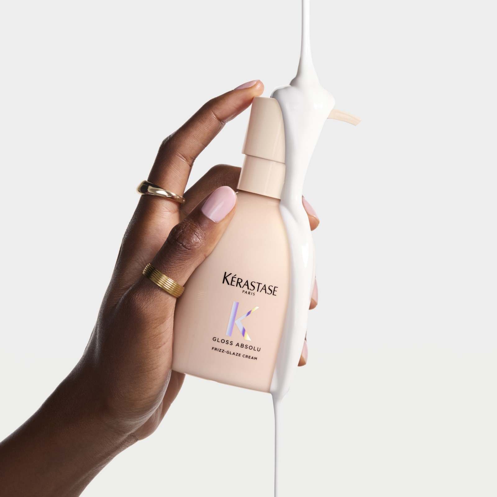 Kérastase Gloss Absolu krém na vlasy v ruce s růžovým nehty na světlém pozadí